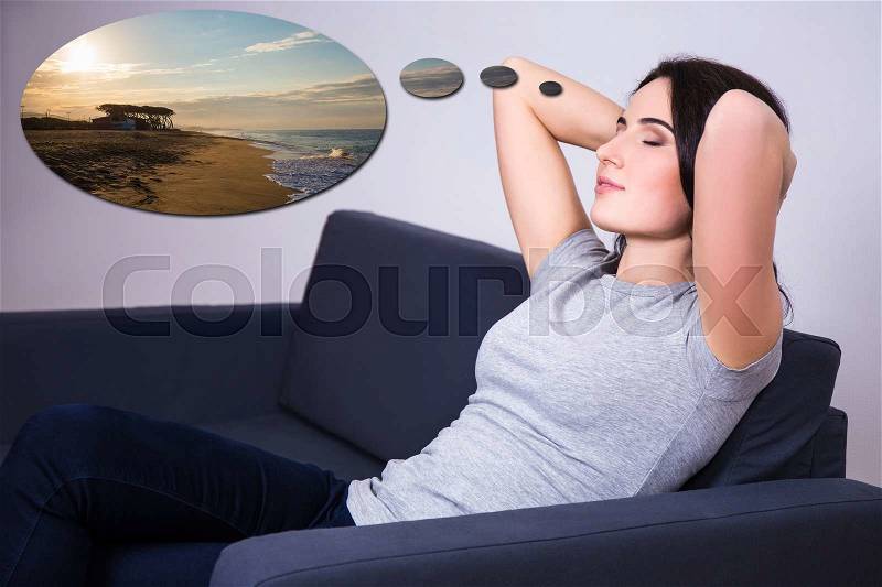 Young woman lying on sofa at home and dreaming about summer vacation, stock photo