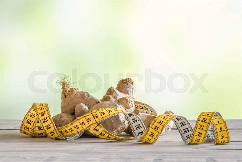 Raw ginger with measure tape on a wooden table, stock photo
