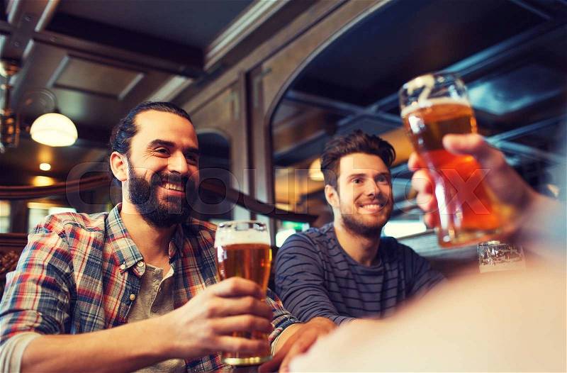 People, leisure, friendship and and bachelor party concept - happy male friends drinking beer at bar or pub, stock photo