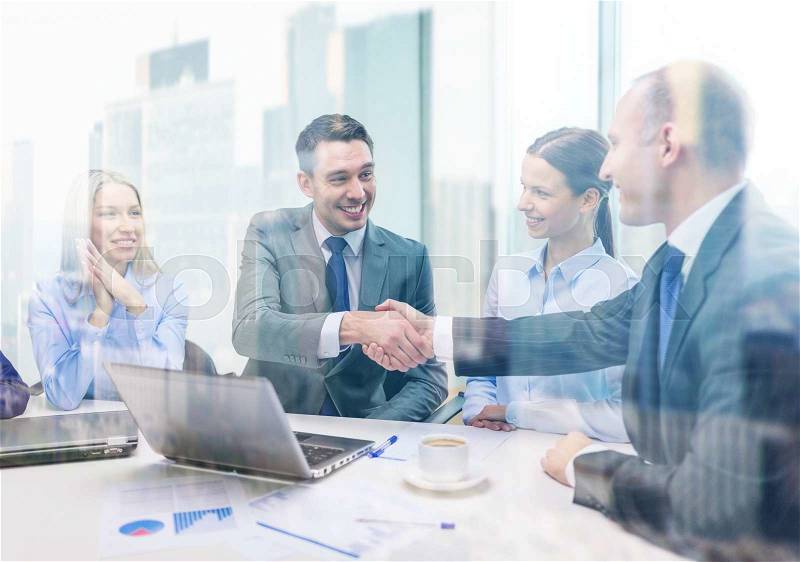 Business, technology and office concept - two smiling businessman shaking hands in office, stock photo