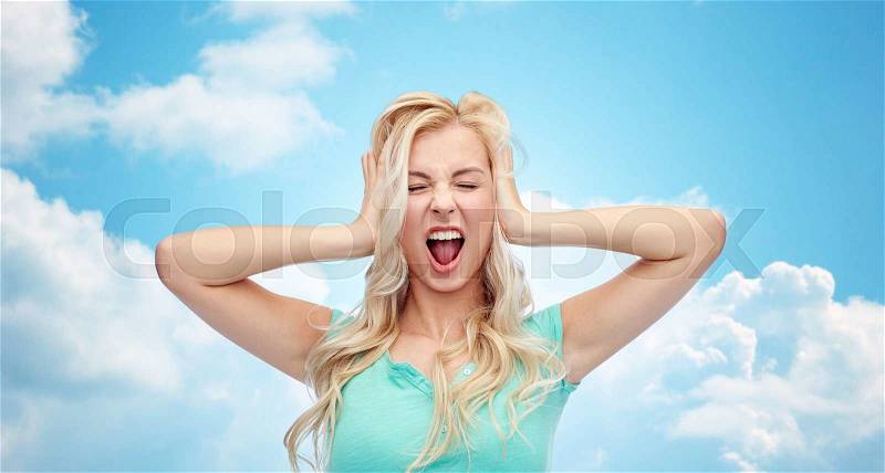 Emotions, expressions, stress and people concept - young woman holding to her head and screaming over blue sky and clouds background, stock photo