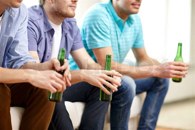 Friendship, leisure, people and alcohol concept - close up of happy male friends drinking beer and watching tv at home, stock photo