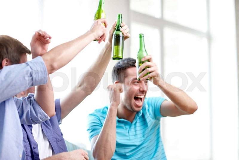 Friendship, leisure, people and alcohol concept - close up of happy male friends drinking beer and celebrating victory at home, stock photo