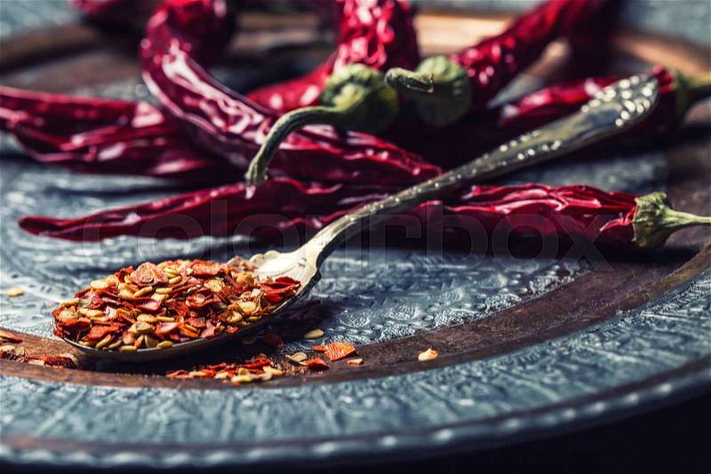 Chili. Chili peppers. Several dried chilli peppers and crushed peppers on an old spoon spilled around. Mexican ingredients - cuisine, stock photo