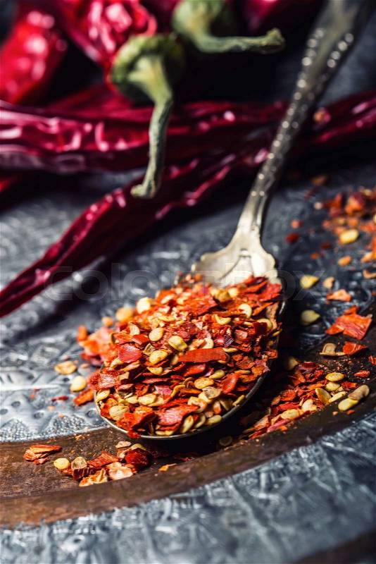 Chili. Chili peppers. Several dried chilli peppers and crushed peppers on an old spoon spilled around. Mexican ingredients - cuisine, stock photo