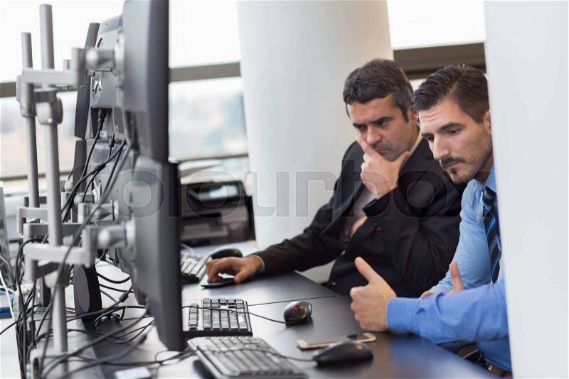 Business team working in corporate office. Businessmen trading stocks. Concerned stock traders looking at graphs, indexes and numbers on multiple computer screens. Business crisis and loss concept, stock photo