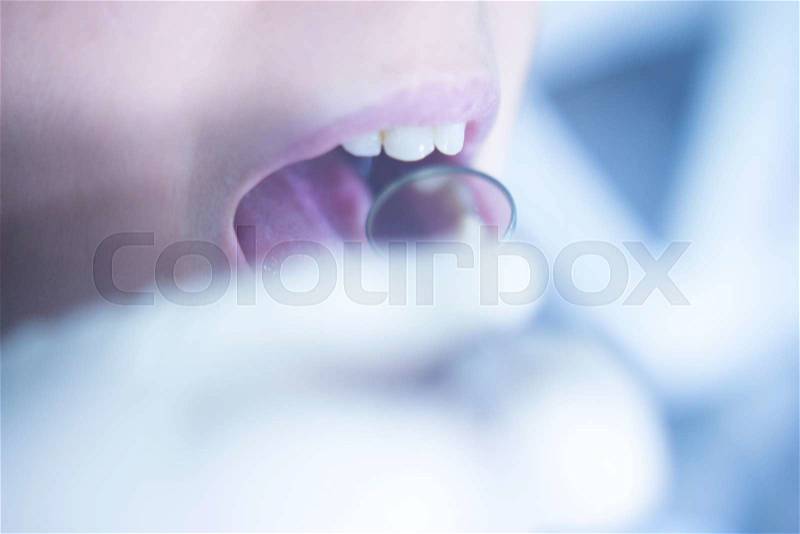 Dentist examining patient mouth in dental exam with dentist\'s instrumentation in clinic, stock photo