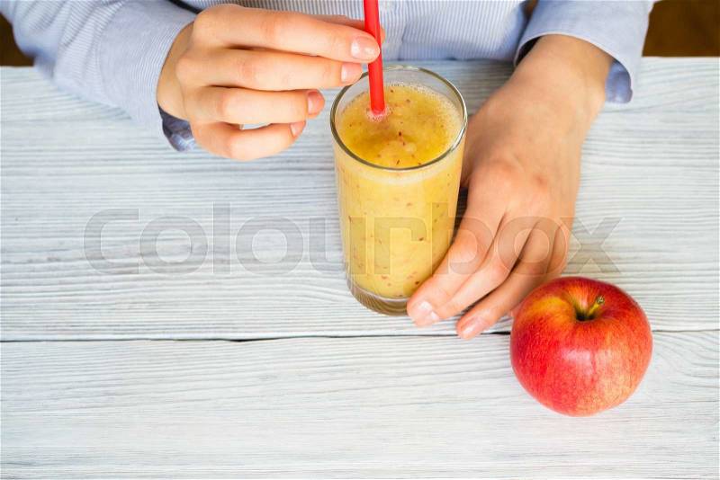 Woman drinks Smoothies from apples and celery in a glass with a straw on a table, top view, stock photo