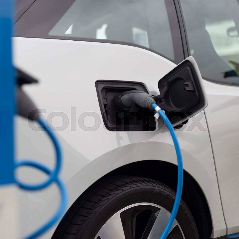 Power supply for electric car charging. Electric car charging station. Close up of the power supply plugged into an electric car being charged, stock photo