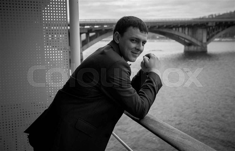 Black and white portrait of handsome businessman posing on balcony, stock photo