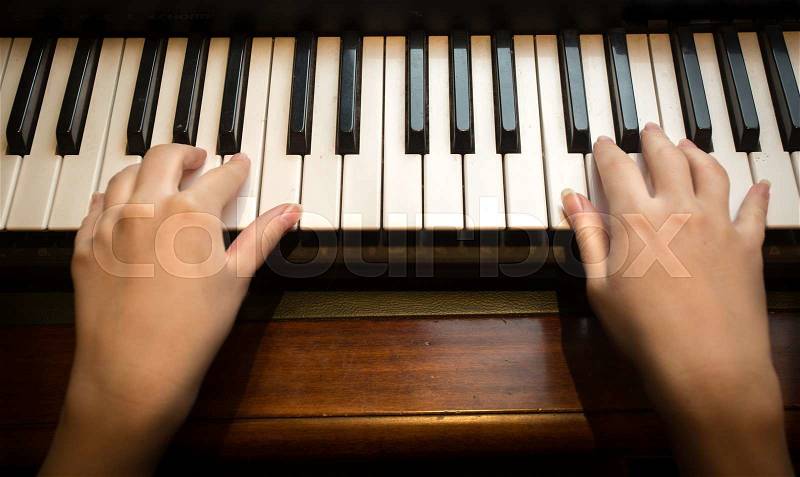 Closeup image of child\'s hands playing on the piano, stock photo