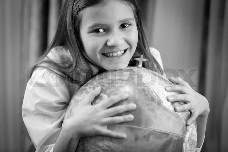 Black and white portrait of smiling girl posing with big Earth globe, stock photo