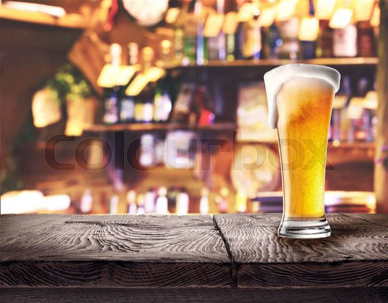 Glass of light beer on wooden board on the bar\'s background, stock photo