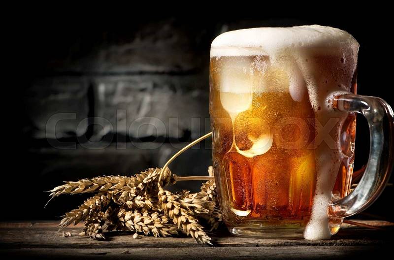 Light beer and wheat near brick wall, stock photo