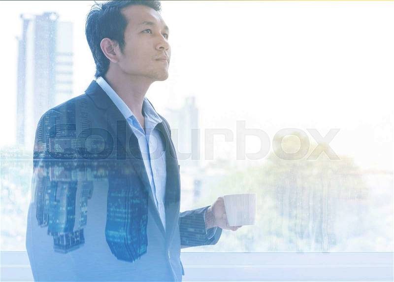 Double exposure of businessman drinking hot coffee by the window with cityscape. , stock photo