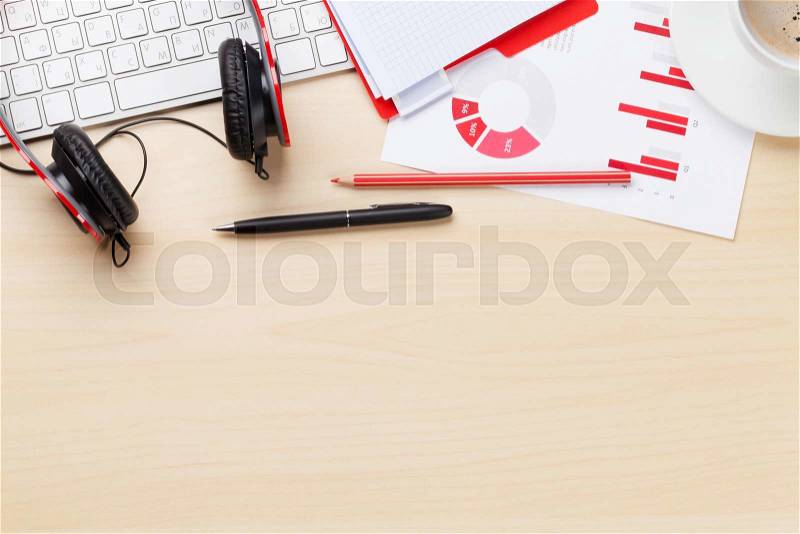Office desk workplace with charts, coffee cup, pc, headphones and notepad on wooden table. Top view with copy space, stock photo