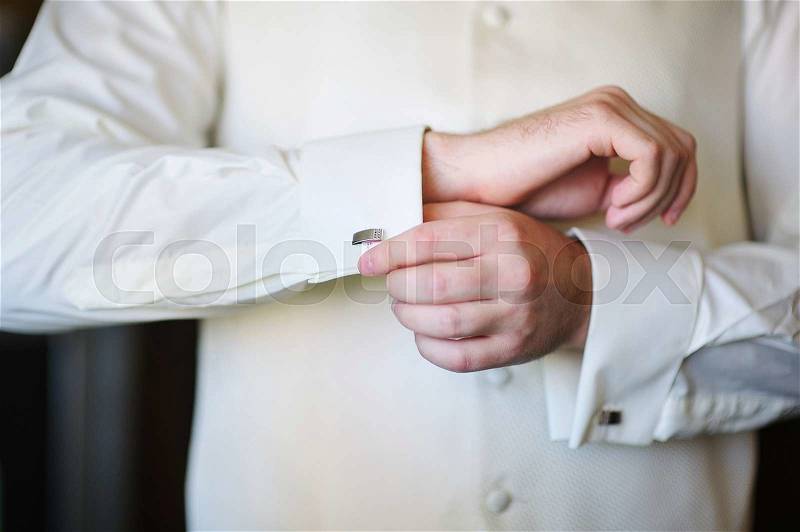 Groom in the morning on the wedding day buttoning cuffs his hands, stock photo