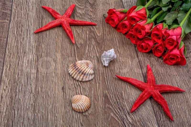 Red starfishes, shells and red roses on a wooden background, stock photo