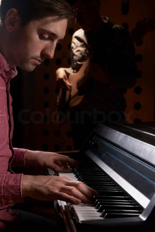 Musicians Playing Electric Piano And Bass Guitar In Recording Studio, stock photo