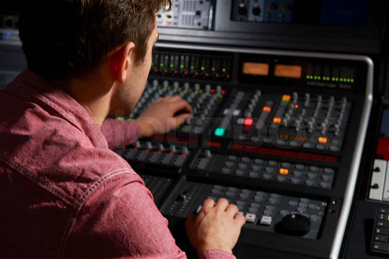 Engineer Working At Mixing Desk In Recording Studio, stock photo
