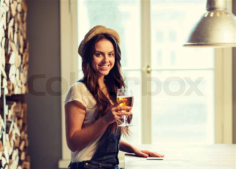People, drinks, alcohol and leisure concept - happy young redhead woman drinking beer at bar or pub, stock photo