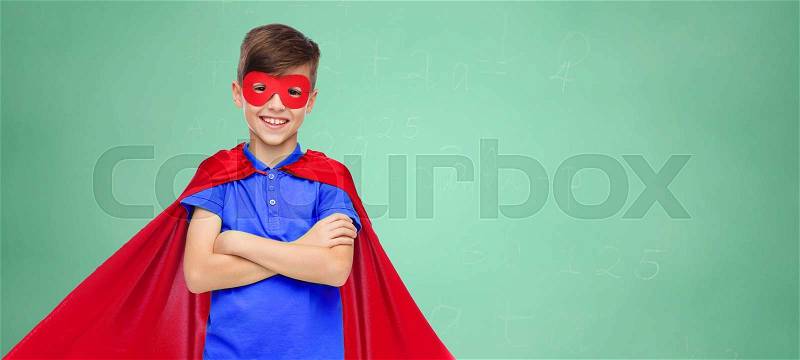 Education, childhood, power and people concept - happy boy in red super hero cape and mask over green school chalk board background, stock photo