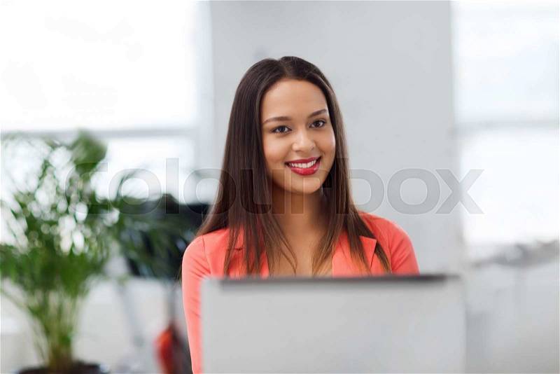 Business, startup, education and people concept - happy young african woman with laptop computer working at office, stock photo