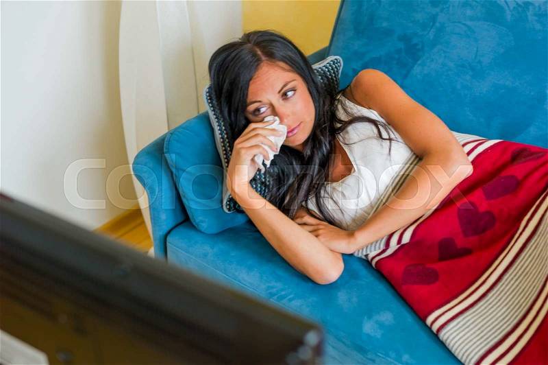 A young woman sees a sad movie on tv, stock photo
