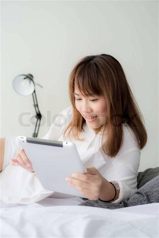 Asian woman laying on floor with tablet, lifestyle concept, stock photo