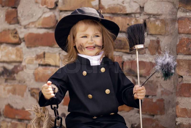 Girl as a chimney sweep against brick wall. , stock photo