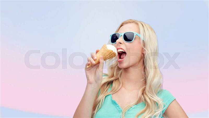 Summer, junk food and people concept - young woman or teenage girl in sunglasses eating ice cream over pink background, stock photo