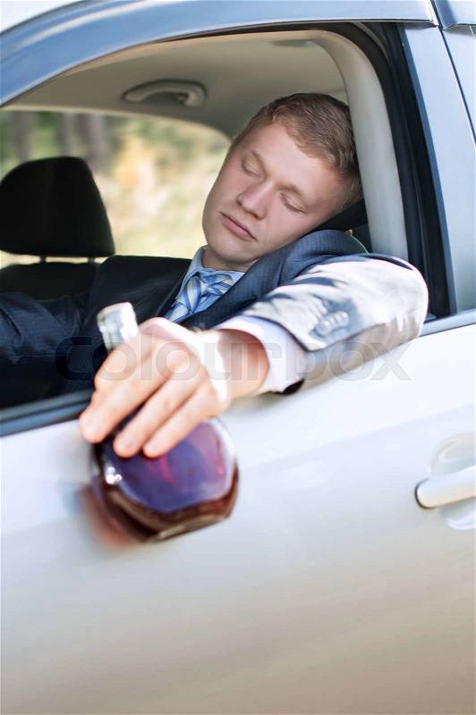 Drunk driver fell asleep at the wheel of a car with a bottle, stock photo