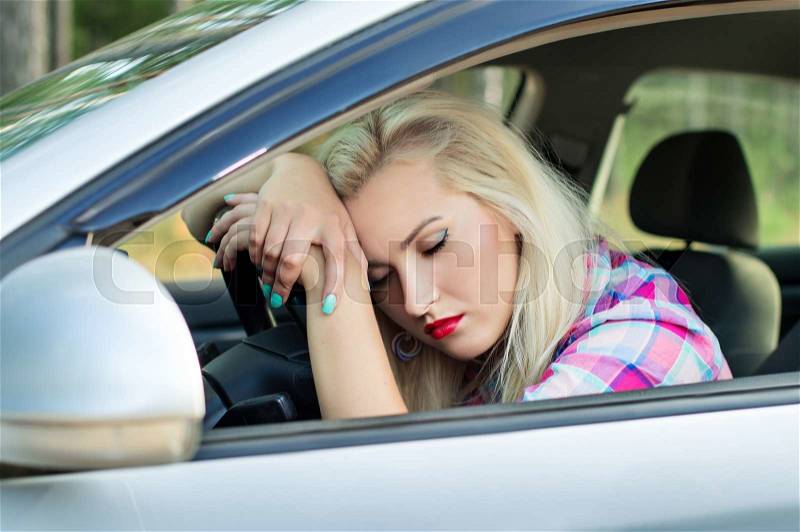 Driver girl was tired and fell asleep at the wheel of a car, stock photo