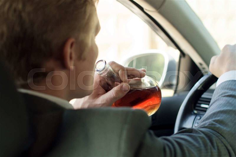 Driver drinks alcohol while sitting behind the wheel of of the car, stock photo