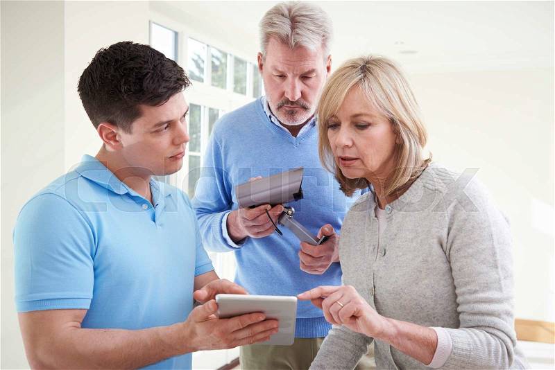 Security Consultant Demonstrating Alarm System To Mature Couple, stock photo