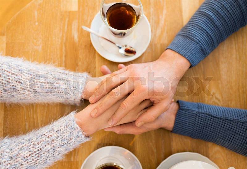 People, love, romance and dating concept - close up of happy couple drinking tea and holding hands at cafe or restaurant, stock photo