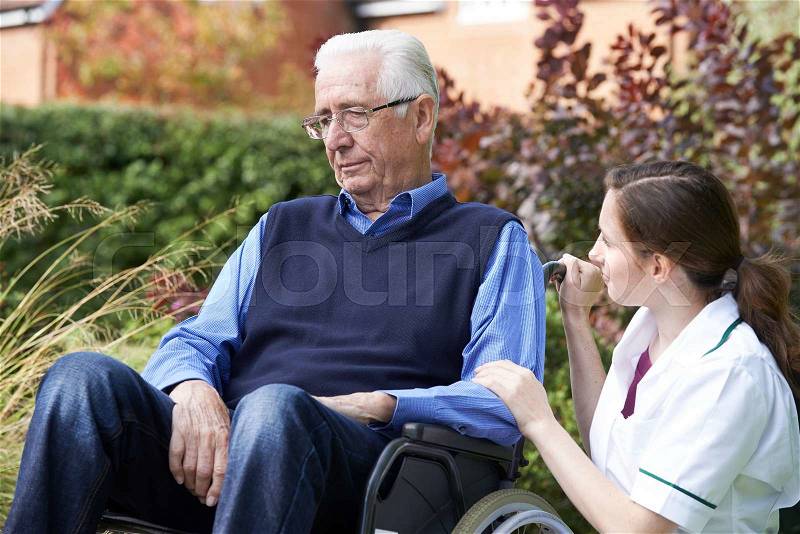 Nurse Comforting Senior Man In Wheelchair, stock photo