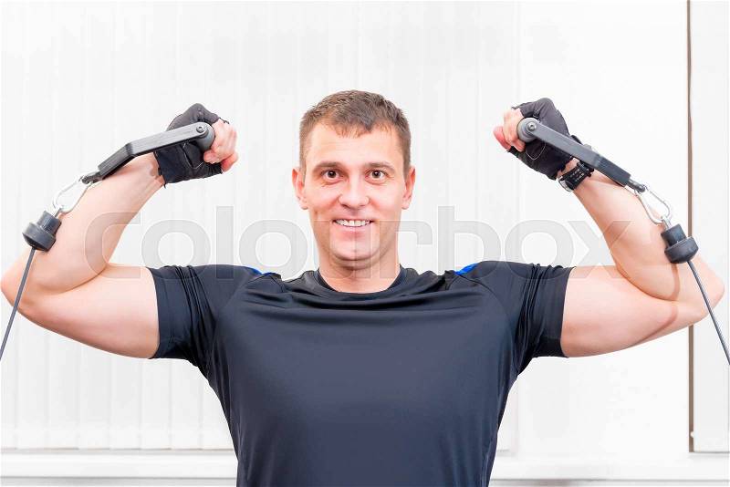 Pretty strong man is engaged in a sports hall, stock photo