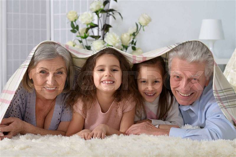 Portrait of a happy senior couple with grandchildren at home, stock photo