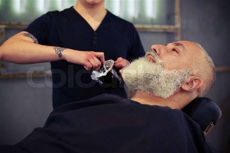 Barber shaving with brush shaving foam an senior man in a barber\'s shop, stock photo