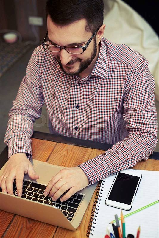 Top view of a smiling working businessman with the glasses who typing on his laptop, stock photo