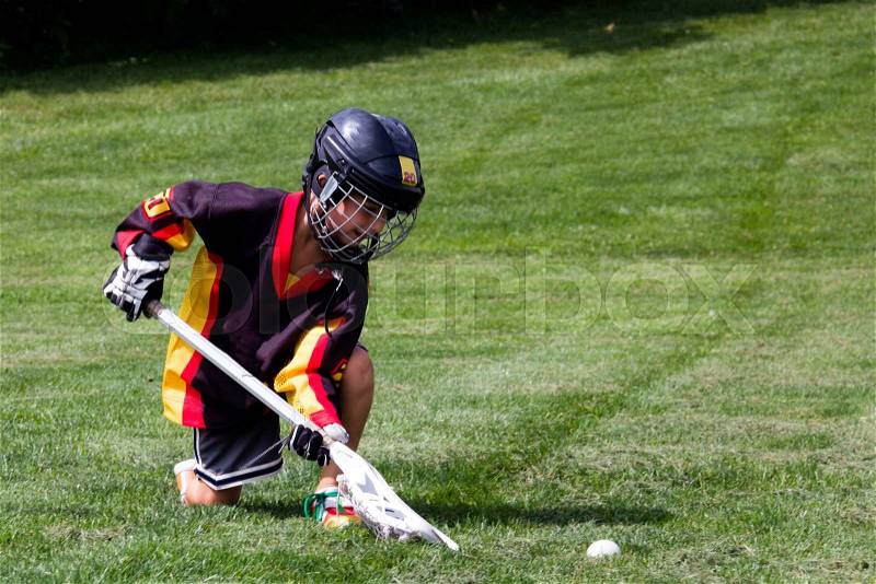 Little boy playing in protective gear lacrosse in the park, stock photo