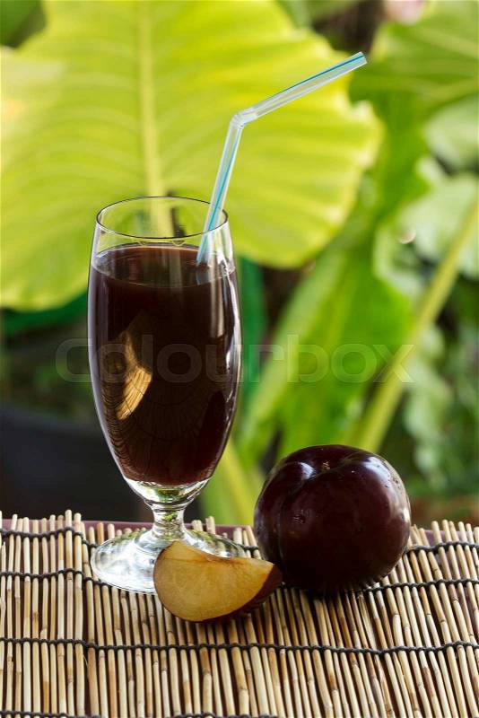 Fresh plums and a glass full of plums juice , stock photo