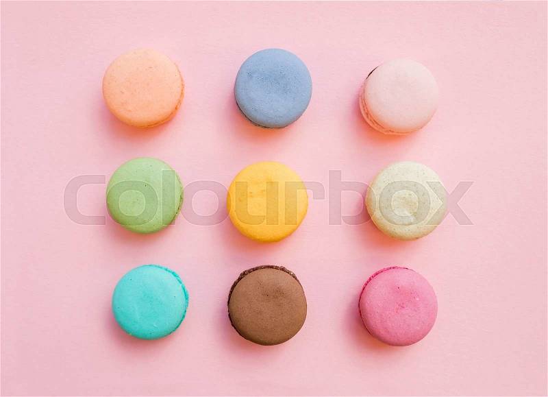 Sweet colorful French macaroon biscuits on pastel pink background, top view, stock photo