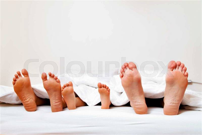 The soles of a family in bed under the covers, stock photo
