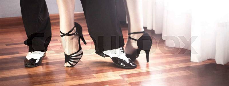 Male and female ballroom, standard, sport dance, latin and salsa couple dancers feet and shoes in dance academy school rehearsal room dancing salsa, stock photo