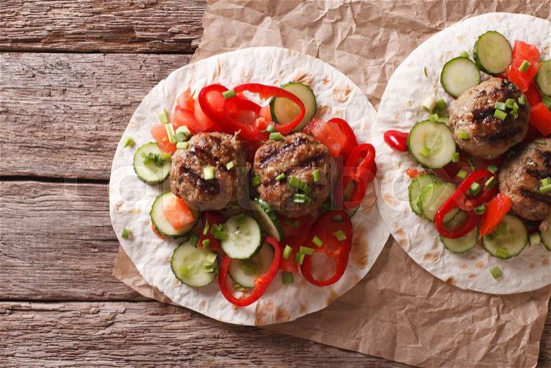Grilled meat balls with fresh vegetables on a flat bread on the table. horizontal view from above , stock photo