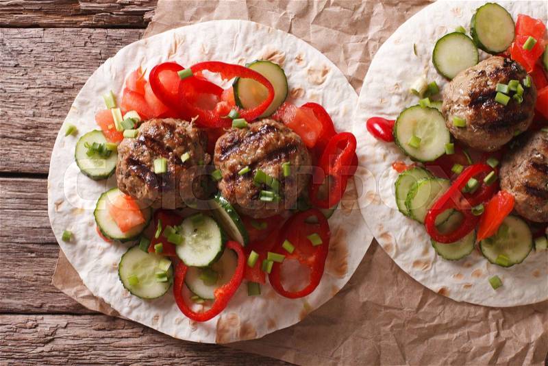 Grilled meat balls with fresh vegetables on a flat bread close up on the table. horizontal view from above , stock photo