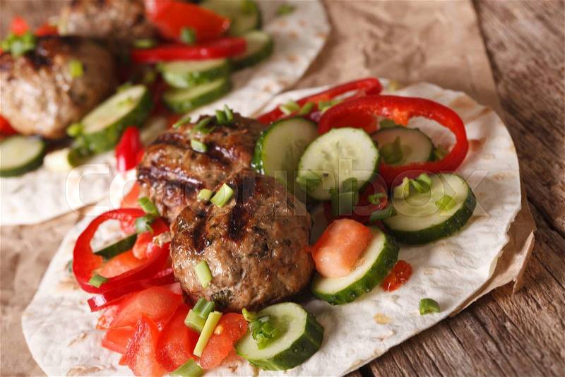 Arabian food: meat balls with fresh vegetables on a flat bread close up on the table. horizontal , stock photo