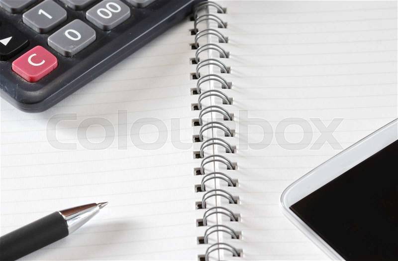 Close up shot of hand held calculator, silver pen and notepad in horizontal layout, stock photo